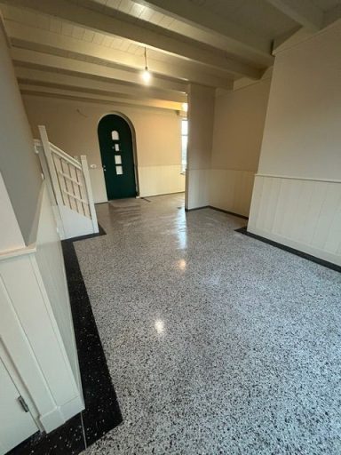 terrazzo hal Zicht op een ruime gang met een groen deur en een glanzende tegelvloer.