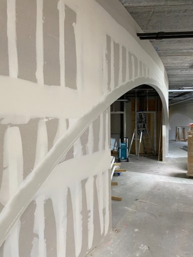 wandafwerking Gedeeltelijk afgewerkte muur met boog en bouwmaterialen op de achtergrond.